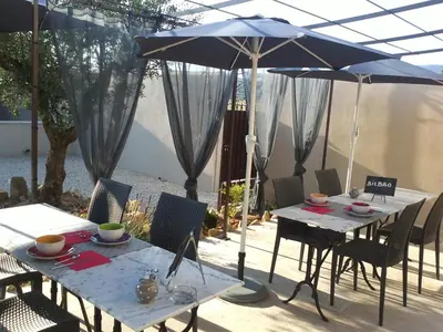 a patio with two tables and an umbrella at Mas Dansavan Chambres d'hôtes in Oppède
