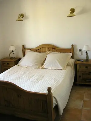 a bedroom with a wooden bed with white sheets and pillows at Demeure d'hôtes et Mas Maurice in Oppède
