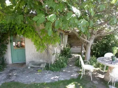 a patio with a table and chairs under a tree at La Source à Bonnieux en Luberon in Bonnieux