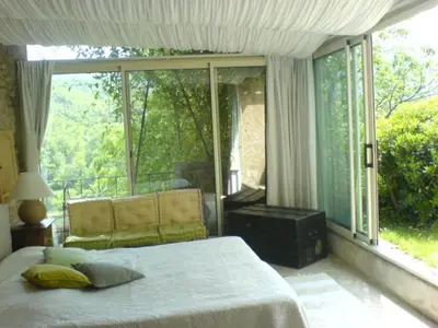 a bedroom with a bed and a large window at La Source à Bonnieux en Luberon in Bonnieux