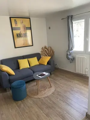 a living room with a blue couch and yellow pillows at T2 de la Bastide Rouge vue exceptionnelle (180°) sur Aix domaine privé T2 indépendant de 37 m2 avec terrasse exposée plein sud Piscine 10 X 5 in Aix-en-Provence