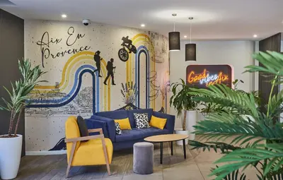 a living room with a blue couch and a mural at Appart'hôtel Odalys City - Aix en Provence Centre Palais des Congrès in Aix-en-Provence