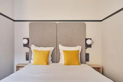 a bedroom with a large bed with yellow pillows at Appart'hôtel Odalys City - Aix en Provence Centre Palais des Congrès in Aix-en-Provence