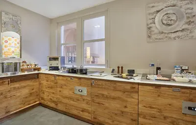 a kitchen with wooden cabinets and a window at Appart'hôtel Odalys City - Aix en Provence Centre Palais des Congrès in Aix-en-Provence