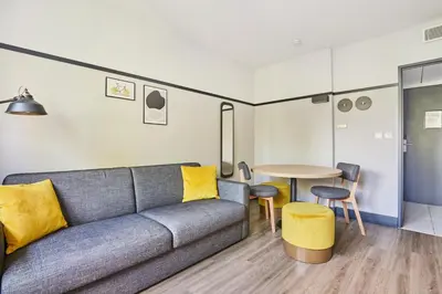 a living room with a couch and a table at Appart'hôtel Odalys City - Aix en Provence Centre Palais des Congrès in Aix-en-Provence