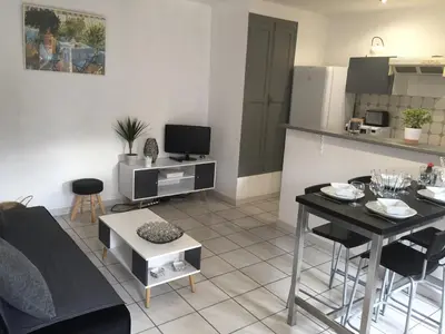a living room with a table and a kitchen at T2 avec TERRASSE, CLIM , box fibre in Vedène