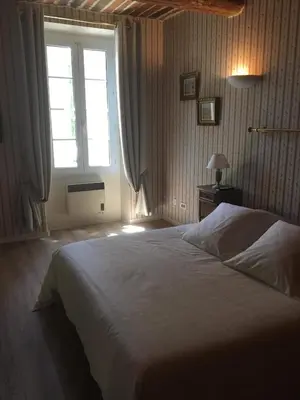 a bedroom with a large bed and a window at Le Cheval Blanc in La Bastide-des-Jourdans