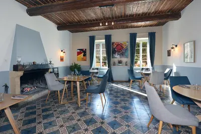 a restaurant with tables and chairs and a fireplace at Le Cheval Blanc in La Bastide-des-Jourdans