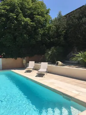 a pool with two chairs and a dog laying next to it at Le Cheval Blanc in La Bastide-des-Jourdans