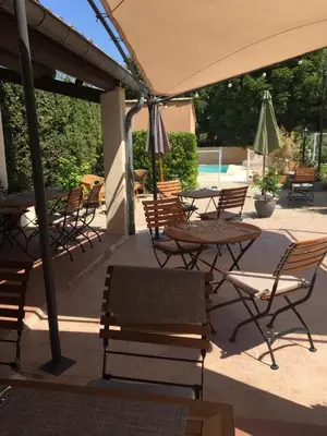 a patio with tables and chairs and an umbrella at Le Cheval Blanc in La Bastide-des-Jourdans