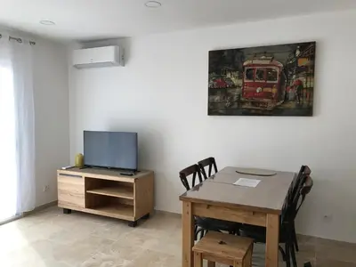 a dining room with a table and a tv at Le Devem De Mirapier in Cornillon-Confoux