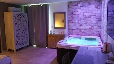 a bathroom with a hot tub with a brick wall at Le Devem De Mirapier in Cornillon-Confoux