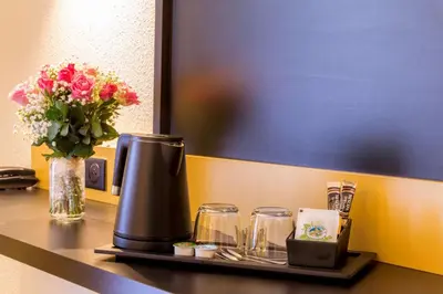 a table with a coffee maker and a vase of flowers at Best Western Domaine de Roquerousse in Salon-de-Provence