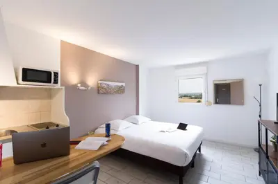 a hotel room with a bed and a desk with a laptop at Garden & City Aix En Provence - Puyricard in Aix-en-Provence