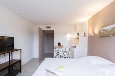 a bedroom with a white bed and a table at Garden & City Aix En Provence - Puyricard in Aix-en-Provence