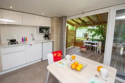 a small house with a roof and a patio at Camping Les Hautes Prairies in Lourmarin