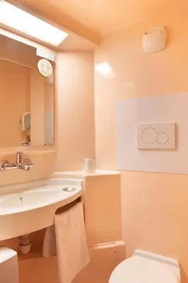 a bathroom with a sink and a toilet and a mirror at Premiere Classe Avignon Parc Des Expositions in Montfavet