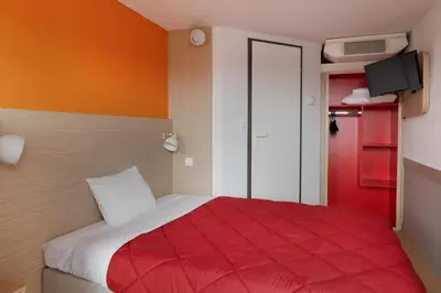 a bedroom with a bed with a red blanket at Premiere Classe Avignon Parc Des Expositions in Montfavet