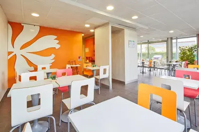 a dining room with white tables and colorful chairs at Premiere Classe Avignon Parc Des Expositions in Montfavet