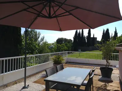 a table and chairs under an umbrella on a deck at Suite l'Escoundudo in Aix-en-Provence