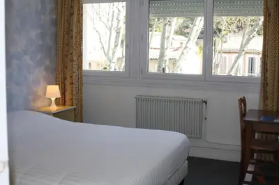 a bedroom with a white bed and two windows at Hotel du Midi in Salon-de-Provence