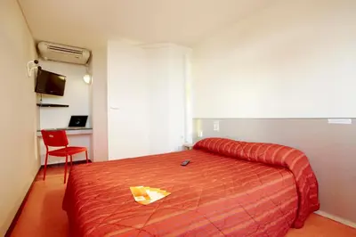 a bedroom with a bed with a yellow paper on it at Premiere Classe Salon De Provence in Salon-de-Provence