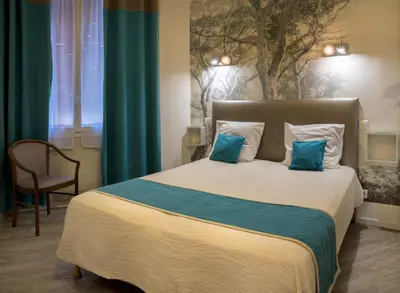 a bedroom with a large bed with blue pillows at Hotel Toppin in Cavaillon
