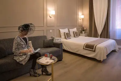 a woman sitting on a couch in a hotel room at Hotel Toppin in Cavaillon