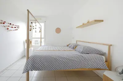 a white bedroom with a bed with a wooden frame at T2 cosy proche du centre-ville avec garage inclus in Aix-en-Provence