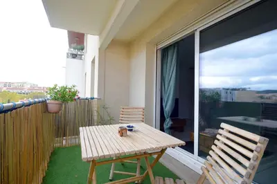 a wooden table and two chairs on a balcony at T2 cosy proche du centre-ville avec garage inclus in Aix-en-Provence