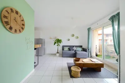 a living room with a couch and a clock on the wall at T2 cosy proche du centre-ville avec garage inclus in Aix-en-Provence
