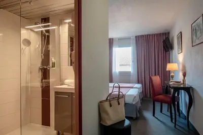 a hotel room with a bathroom with a bed and a shower at Hotel du Forum in Carpentras