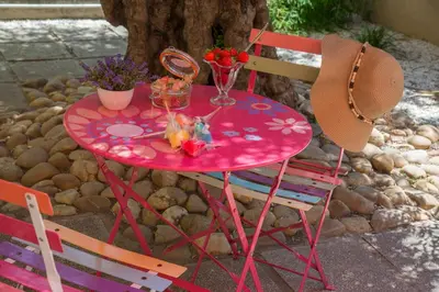 a pink table with two chairs and flowers on it at Hotel du Forum in Carpentras