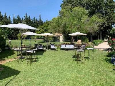 a group of chairs and tables with umbrellas on the grass at Moulin de la Roque in Althen-des-Paluds