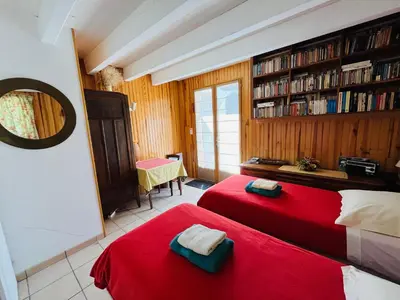 a bedroom with two red beds and a book shelf at L'Atelier de Maia in Mormoiron