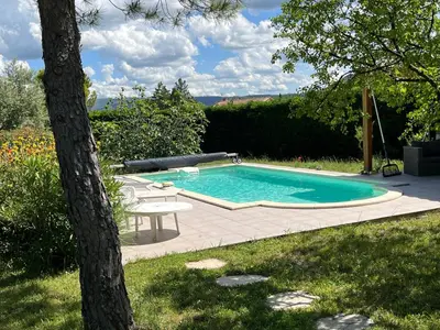 a swimming pool in a yard with a table and a tree at L'Atelier de Maia in Mormoiron