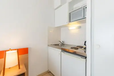 a kitchen with white cabinets and a sink at Appart'City Classic Aix-en-Provence - La Duranne in Aix-en-Provence