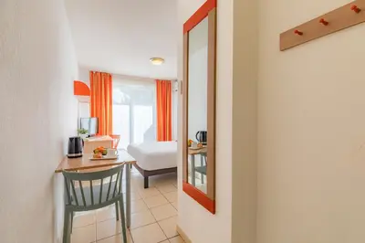 a room with a table and a chair and a mirror at Appart'City Classic Aix-en-Provence - La Duranne in Aix-en-Provence