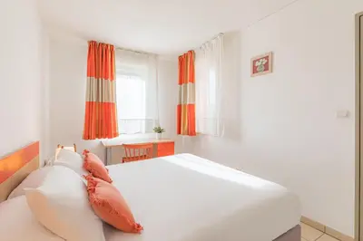 a white bedroom with a large white bed with pillows at Appart'City Classic Aix-en-Provence - La Duranne in Aix-en-Provence