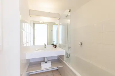 a white bathroom with a sink and a shower at Appart'City Classic Aix-en-Provence - La Duranne in Aix-en-Provence