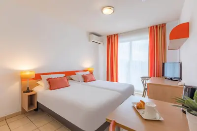 a hotel room with a large bed and a desk at Appart'City Classic Aix-en-Provence - La Duranne in Aix-en-Provence