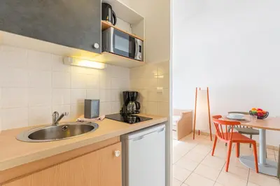 a small kitchen with a sink and a table at Appart'City Classic Aix-en-Provence - La Duranne in Aix-en-Provence
