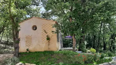 a small building in the middle of a yard with trees at Le Cabanon in Sainte-Croix-à-Lauze