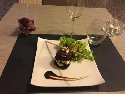 a white plate with a dessert and salad on a table at Logis Hôtel Le Manoir - Luberon in Apt