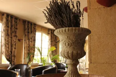 a vase sitting on a table with flowers in it at Logis Hôtel Le Manoir - Luberon in Apt