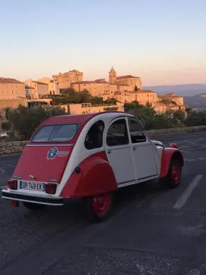 a small red and white car driving down a road at Logis Hôtel Le Manoir - Luberon in Apt