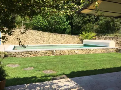 a swimming pool in a yard with a stone wall at typical provencal bastide, built of local stones, in the luberon in cheval-blanc with secured pool and wifi -sleeps 6 people. in Cheval-Blanc