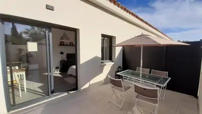 a balcony with a glass table and chairs and an umbrella at Villa Quatra aux portes d'Aix-en-Provence in Éguilles