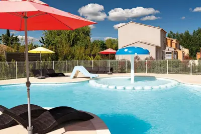 a swimming pool with a red umbrella and some chairs at Lagrange Vacances L’Oustau de Sorgue in LʼIsle-sur-la-Sorgue