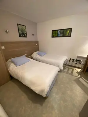 a room with two beds and a chair at HOTEL RESTAURANT OLYMPE in Aix-en-Provence